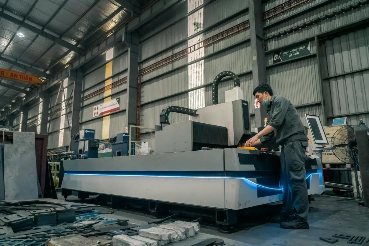 CNC manufacturing floor with operator at laser cutting machine